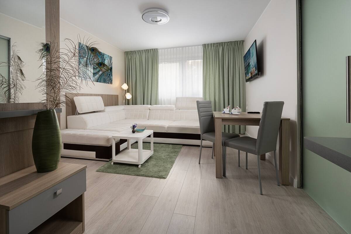 A modern living room with a sofa, a dining table, and a TV.