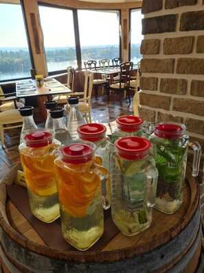 A dining area with a view of a lake, featuring a wooden table and chairs, and several large glass containers with red lids on a wooden barrel. - Hotel Mainzer Hof (Mainz)