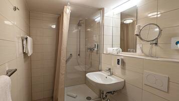 Un baño moderno con ducha, lavabo, inodoro y espejo.