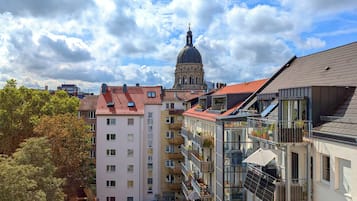 A multi-story building with balconies, a red-tiled roof, and a dome structure in the background.