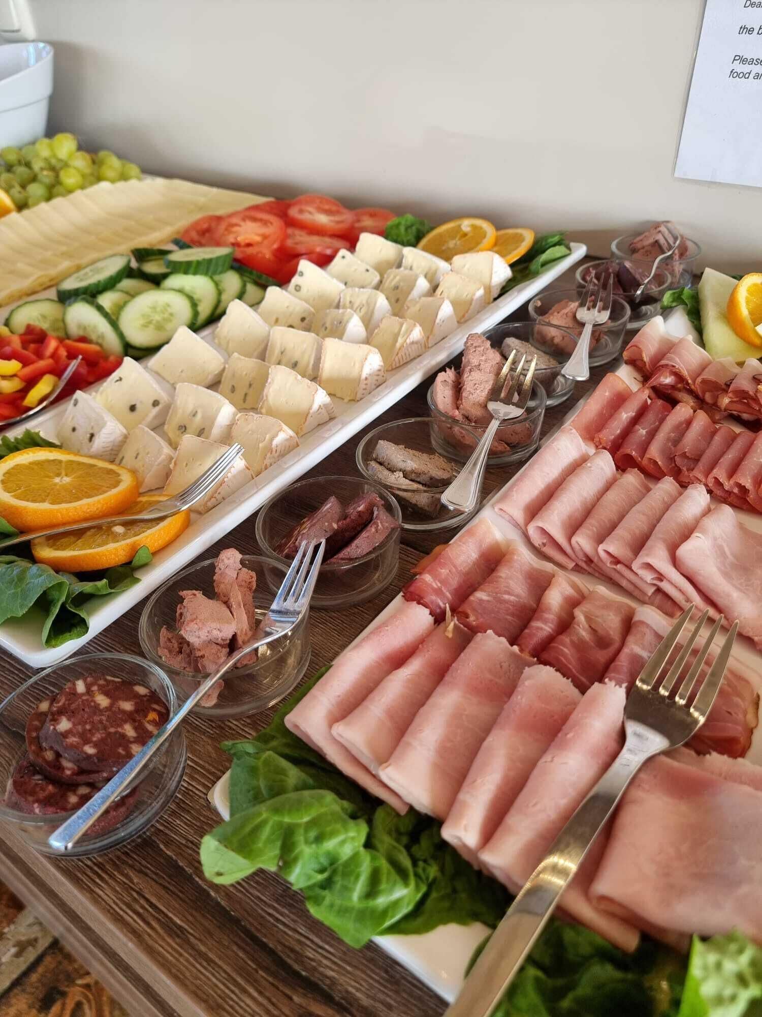 Una mesa de buffet con diversos alimentos, incluyendo quesos, carnes y verduras.
