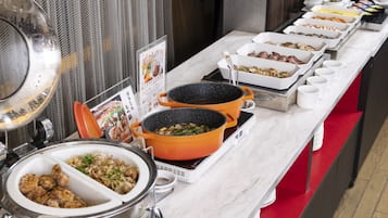 A buffet setup with various dishes and cooking equipment.