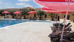 A swimming pool with lounge chairs and red umbrellas. - Nefama Blue Pensão Apt5 (Ourique)
