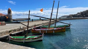 Un port où sont amarrés des bateaux, un phare et un mur de pierre.