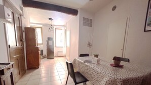 Un coin repas avec une nappe à motifs, un réfrigérateur et une chaise.