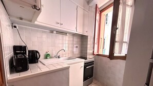 Une cuisine de taille réduite, avec des meubles blancs, un évier, une cuisinière et une fenêtre donnant sur un paysage agréable.