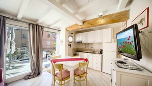 Eine moderne Küche mit weißen Schränken, Holzboden und einem Essbereich mit zwei Stühlen und einem Tisch.