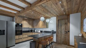 Eine moderne Küche mit Holzbalken, Edelstahlgeräten und einer zentralen Kochinsel mit Barhocker.