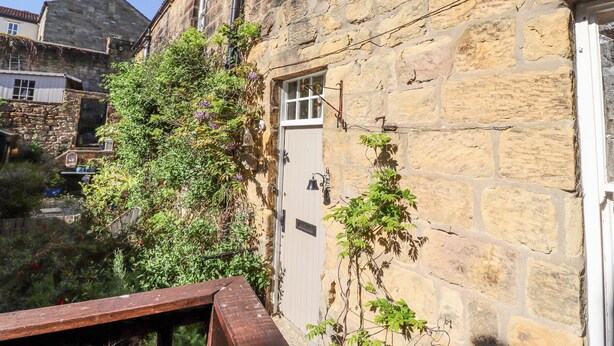 Un bâtiment en pierre avec une porte en bois, une fenêtre et un petit balcon.