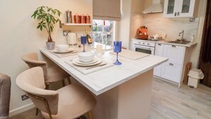 Une cuisine moderne dotée d’un îlot central, de meubles blancs et d’une fenêtre laissant entrer la lumière naturelle.
