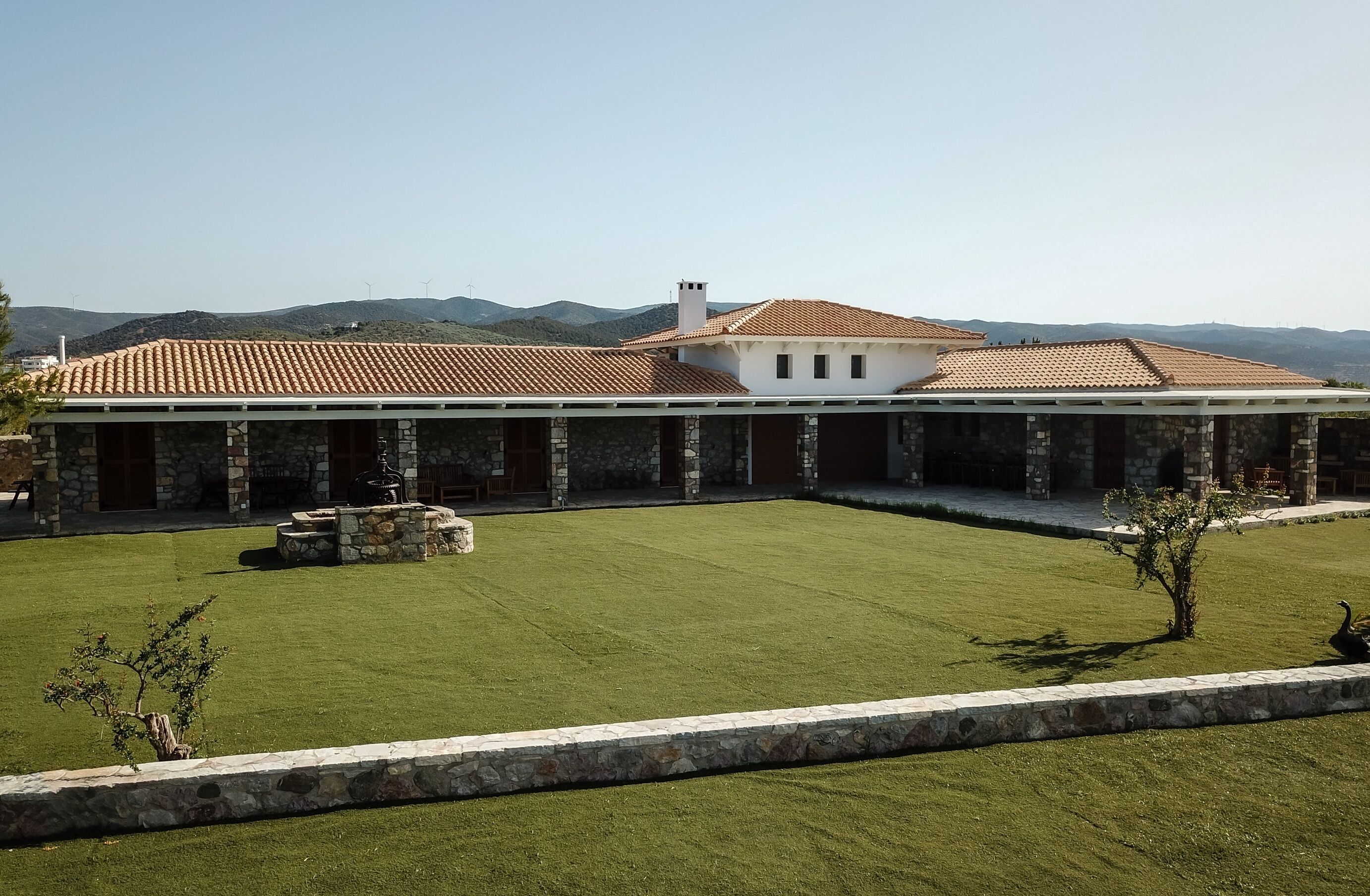 A stone building with a tiled roof, a stone patio, and a well-maintained lawn.