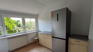 A kitchen with a built-in refrigerator, a window with a view of greenery, and a radiator. - Ferienwohnung Family Basic in Kiel (Kiel)