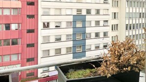 Un edificio de varios pisos con una mezcla de estilos arquitectónicos, incluyendo un edificio rojo con balcones y un edificio beige con una franja azul.