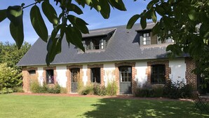 A two-story house with a brick facade, a sloped roof, and a well-maintained lawn.