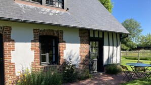 A traditional house with a brick facade, a sloped roof, and a small garden area with a table and chairs.