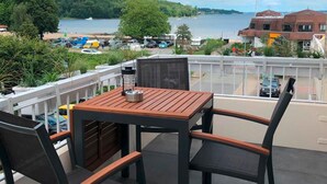 A balcony with a table and chairs overlooking a beach and a body of water. - fewo1846 - MuschelNest (App. (Harrislee)