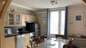Une cuisine avec des meubles en bois, un réfrigérateur en acier inoxydable, un lave-vaisselle et une table à manger avec des chaises.