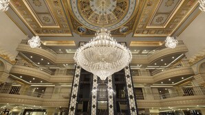 Un vaste hall d’entrée agrémenté d’un grand lustre, d’un plafond richement décoré et de plusieurs balcons.