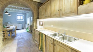 Una cocina con armarios de madera, un fregadero y una zona de comedor con una mesa y sillas.