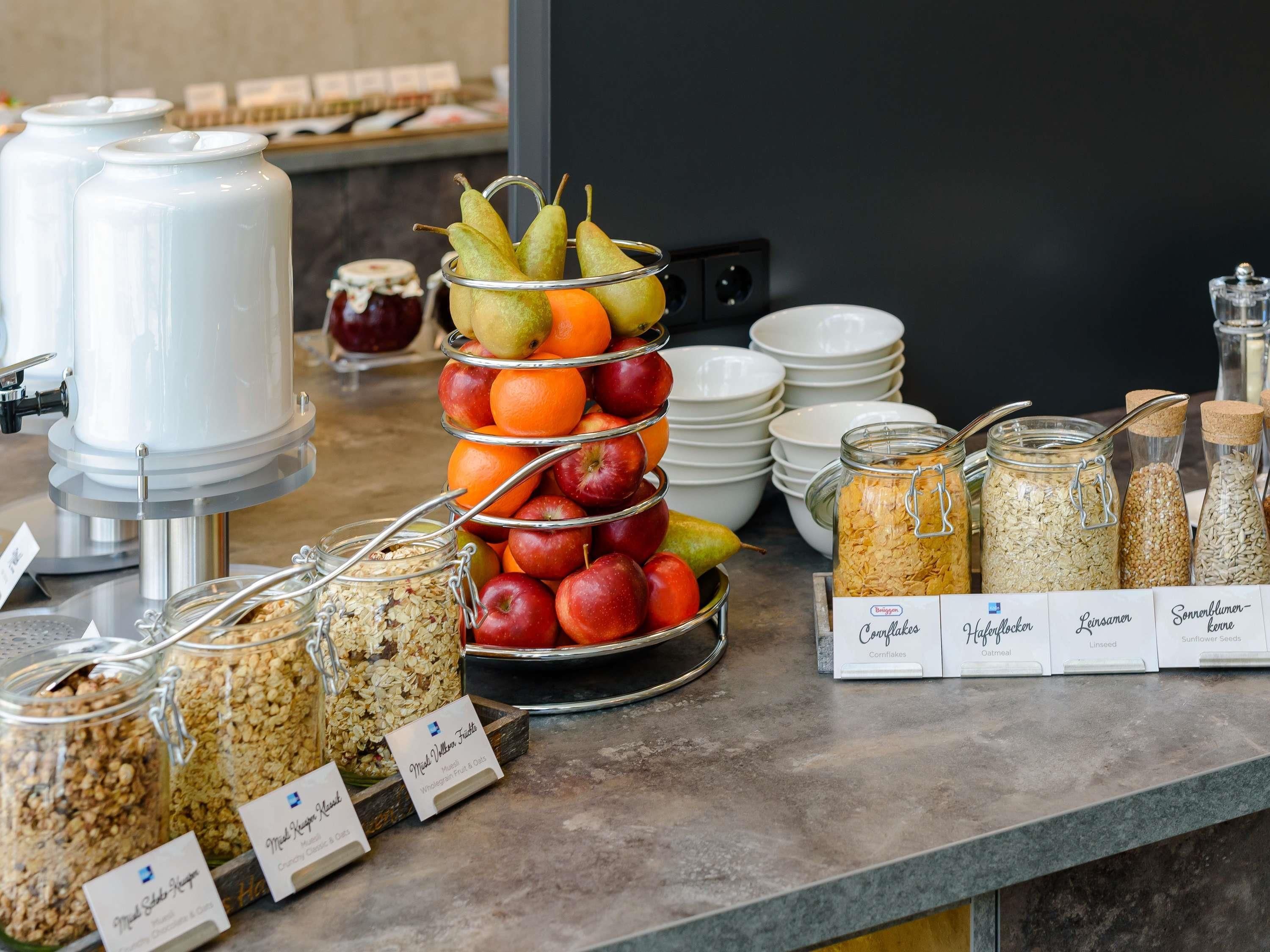 A buffet setup with various food items, including fruits, cereals, and labeled containers.