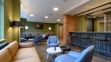 Eine moderne Lounge mit einer Couch, Sesseln, einem kleinen Tisch und einer Bar mit Hockern.