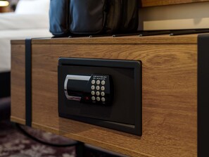 Habitación de hotel con un cajón de madera que contiene un dispositivo electrónico negro, posiblemente una caja fuerte o sistema de bloqueo.
