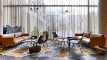 Un salon moderne avec des canapés en cuir, un tapis à motifs et une grande fenêtre ornée de rideaux légers.