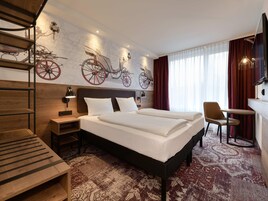 Quarto de hotel com cama, escrivaninha, cadeira, televisão e escada.