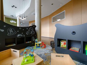 A children's play area with a bear-shaped bookshelf, a play table, and a hanging light fixture.