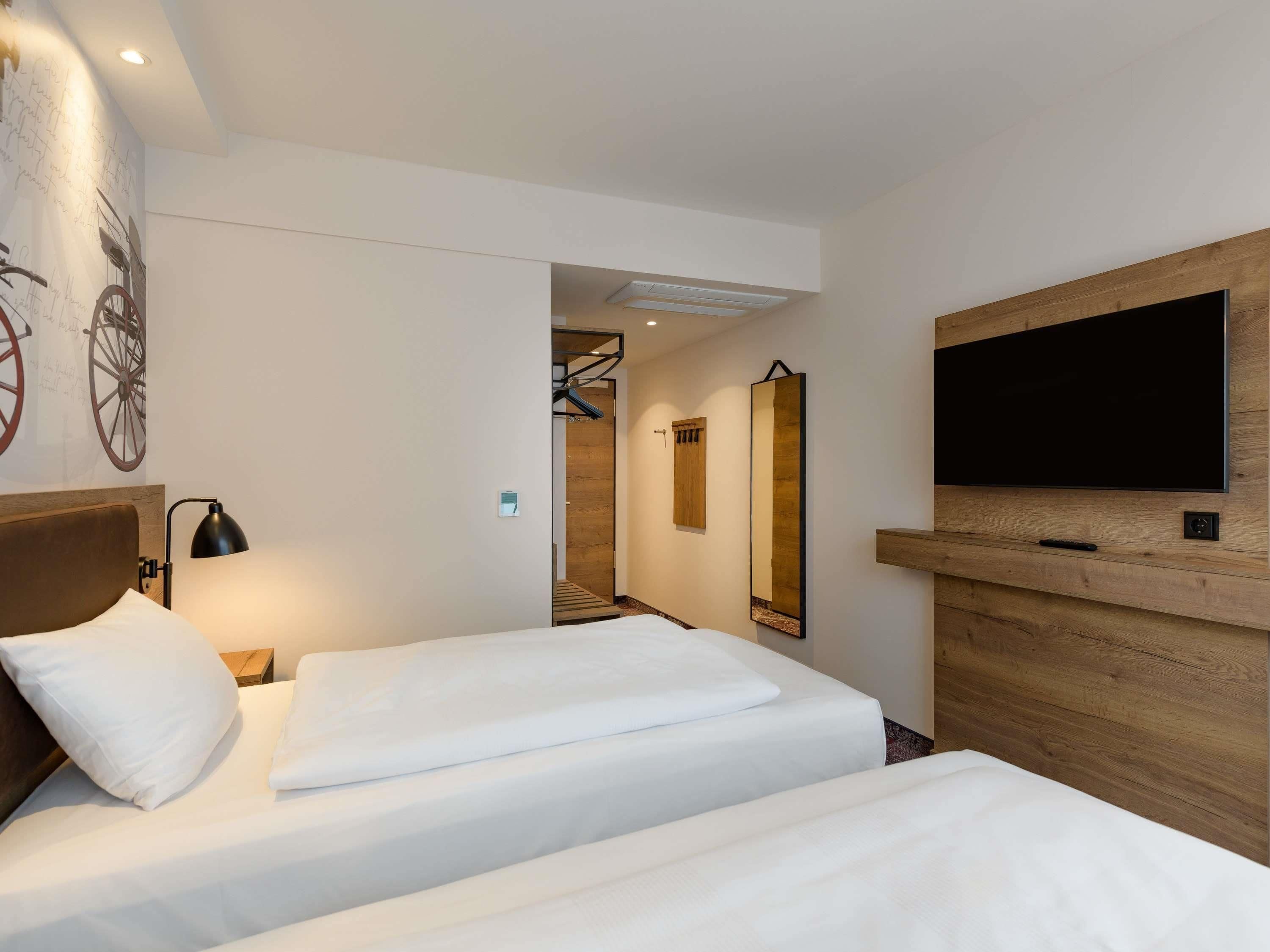 Hotelkamer met twee bedden, een televisie, een spiegel en een muur met een ontwerp van een fietswiel.