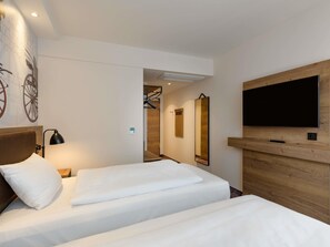 Habitación de hotel con dos camas, un televisor, un espejo y una pared con diseño de rueda de bicicleta.