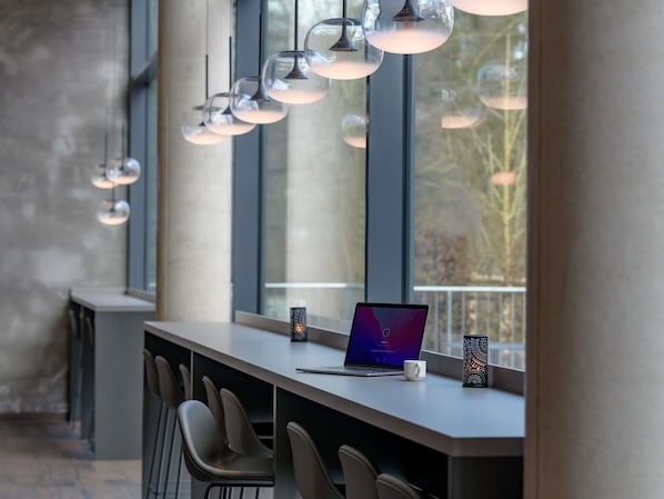Un área de bar moderna con una laptop, una taza y un accesorio de luz decorativo.