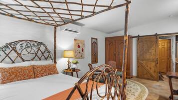 A bedroom with a four-poster bed, a wooden wardrobe, and a door leading to another room.