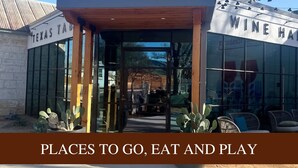 The exterior of Hill & Vine Wine House with a clear entrance, outdoor seating area, and a sign indicating it is a place to go, eat, and play. - Pet Friendly Treehouse Vibe w/ Hot Tub & Fire Pit (Fredericksburg)