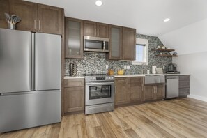 A modern kitchen with stainless steel appliances, wooden cabinets, and a brick backsplash.