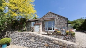 Una cabaña de piedra con un pequeño porche, una ventana y una puerta.
