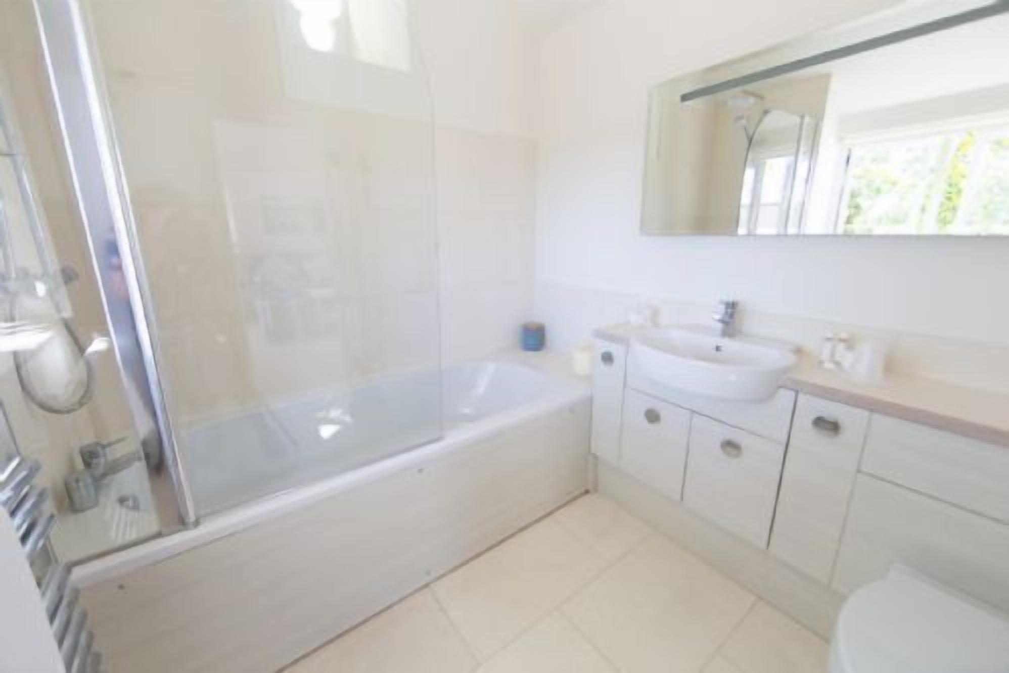 A bathroom with a glass-enclosed shower, a sink, and a toilet.