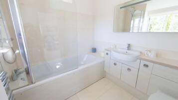 A bathroom with a glass-enclosed shower, a sink, and a toilet.