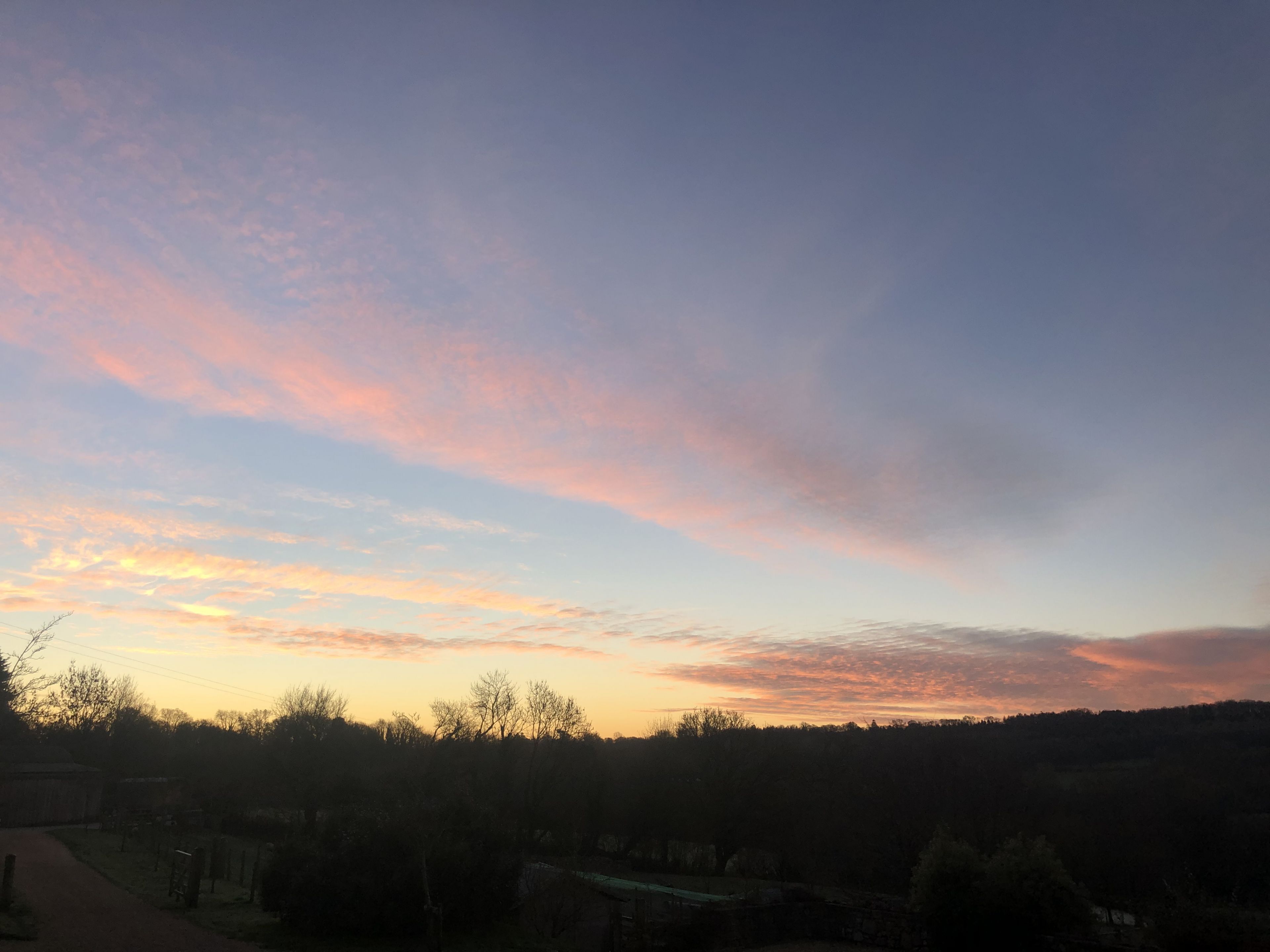 A sunset over a rural landscape with a path leading through a cemetery.