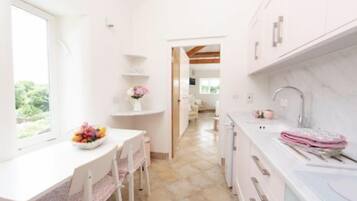 A bright kitchen with white cabinets, a marble countertop, and a window providing natural light.