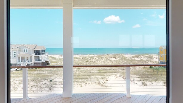 Un balcon avec vue sur la plage et l’océan.