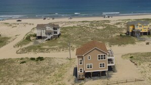 Une propriété située en bord de mer, comprenant plusieurs maisons, une plage de sable et l’océan en toile de fond.