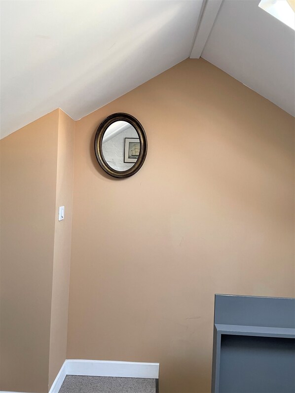 A room with a beige wall, a round mirror, a white baseboard, and a gray cabinet.