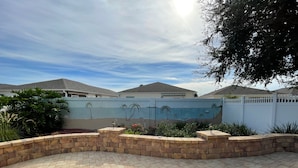 A paved patio area with a decorative wall featuring palm trees and a beach scene.