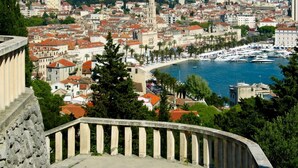 Un paysage urbain côtier avec des bâtiments historiques, un port de plaisance et un escalier en pierre.