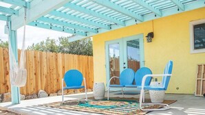 A covered patio with blue chairs and a woven rug.