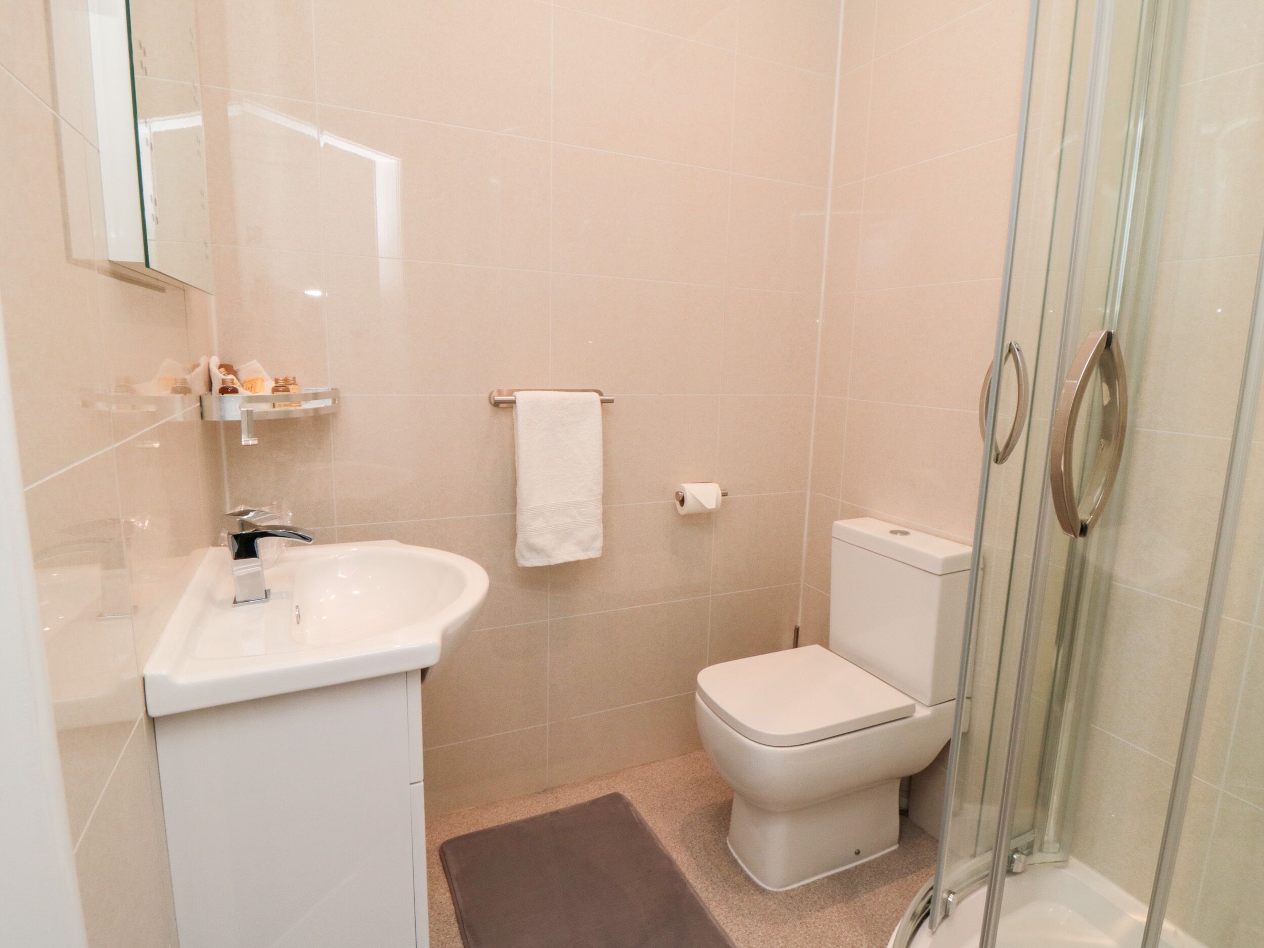 A bathroom with a white sink, toilet, and glass shower enclosure.