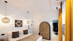Ein modernes Schlafzimmer mit einem großen Bett, zwei Pendelleuchten, einer Wanddekoration und einem Rattanschrank.