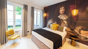 A modern bedroom with a large bed, a chair, a painting, and a view of the outdoors. - Lovelace, 4 stars Residence, Luxury at 50 meters from the Champs-Elysées (París)