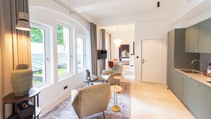 A modern hotel room with a large window, a cozy seating area, a kitchen, and a door leading to another room. - Lovelace, 4 stars Residence, Luxury at 50 meters from the Champs-Elysées (París)